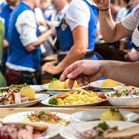 Oktoberfest, Tablett mit mehreren Gerichten wie Schweinebraten, Schnitzel, Pommes, Krautsalat.