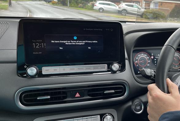 A Hyundai dashboard and central display. The display has a pop up that reads “We have changed our Terms of use and Privacy notice.
Review the change(s)?” and has buttons for yes or no. A person is driving the car and the speedometer reads about 20 mph. Photo is taken from the passenger seat.