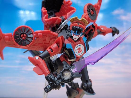 A photo of Transformers Adventure Windblade, in robot mode, in front of a sky backdrop.