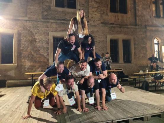 Visitors and organizers of the conference form a human pyramid. 4 people in the base, 3 on top of them, than 2 and finally one person on the top.
