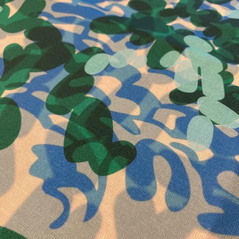 Close-up of abstract printed fabric design. It is of overlapping transparent lozenge shapes with a somewhat leafy and watery nature. Colour palette in pale blue, grey, dark green, blue, and teal. The design name is Ruska 2 version 2 Blue.