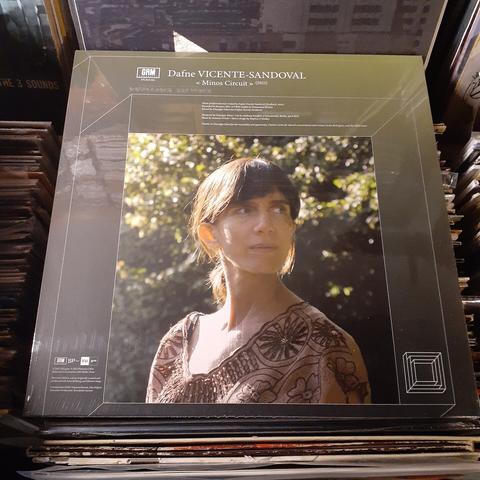 Front album cover features a photo of Dafne Vicente Sandoval, standing in the sunlight with green shrubbery behind her.