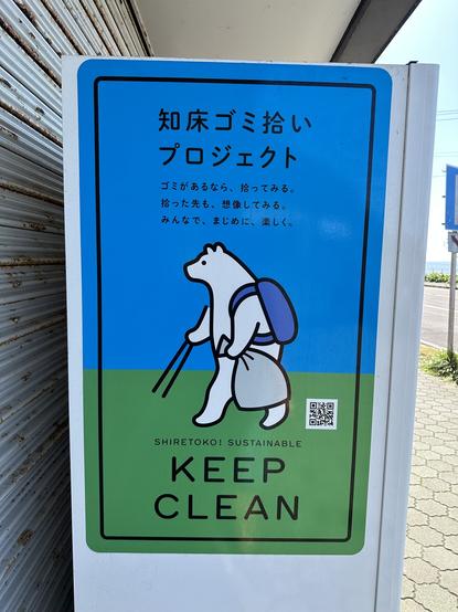 Tokosan wearing a backpack and holding a trash bag and some trash picking tongs on a sigh that says “keep clean”