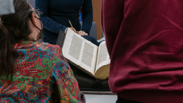 Drei Personen betrachten eine geöffnete mittelalterliche Handschrift. Foto: Universitätsbibliothek Leipzig