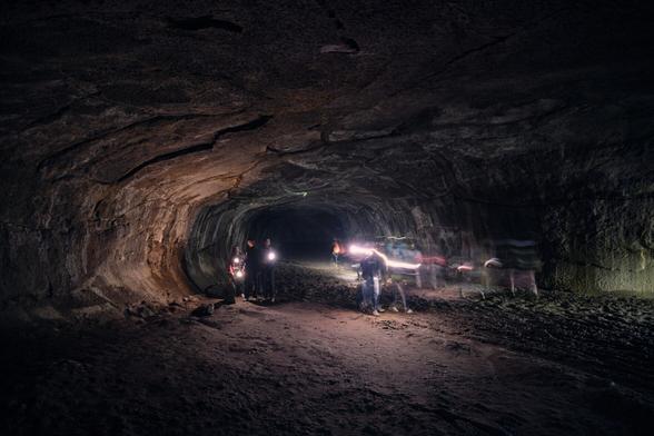 A group of people navigating a dark cave with flashlights.