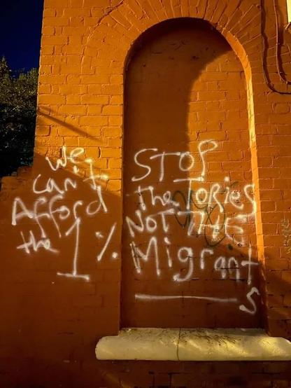"We can't afford the 1%! Stop the Tories not the migrants" written on a wall with white spray paint