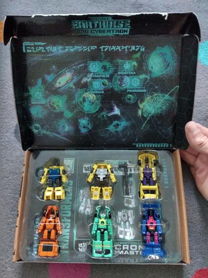 The freshly-opened box of the Transformers Galactic Odyssey Micron Micromasters set, showing a map and the 6 micromaster toys in robot mode.