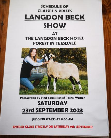The Langdon Beck show catalogue, featuring a woman crouched down, holding a Swaledale sheep. It is printed with today's date and other info such as location, judging time.