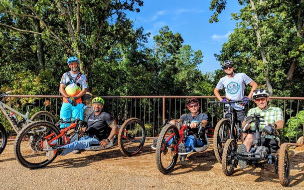 Group of adaptive riders posing with 2 able-bodied support riders