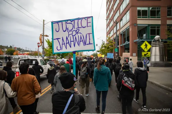 A crowd of hundreds march in the street through Seattle's International District, to mourn the death of at the hands of an SPD officer Jaahnavi Kandula. A sign reads "Justice for Jaahnavi"