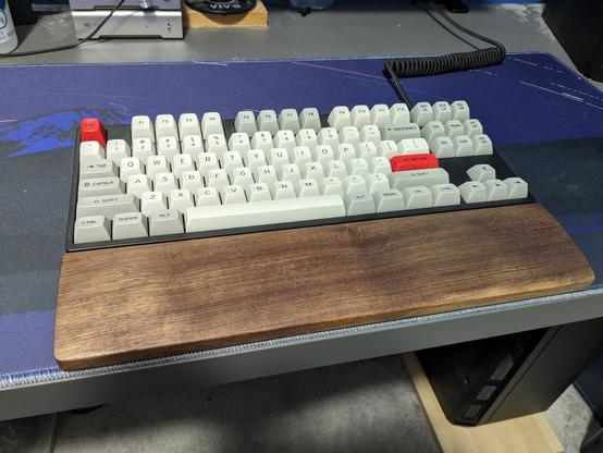 A picture of my modded Cooler Master Novatouch keyboard on my desk, paired with a wooden wristrest and the MT3 /dev/tty custom keycap set.