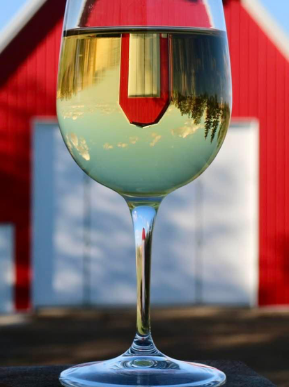 Red barn reflected in a glass of white wine.