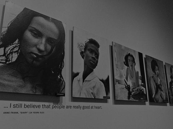 Portrait photos in black and white of young women of different ethnicities. Underneath the first two photos it says "I still believe that people are really good at heart" - Anne Frank, "Diary" (14 years old).