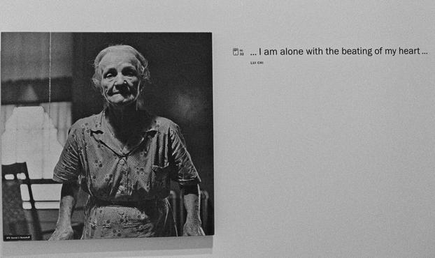 An old woman looking into the camera. Next to the b/w photo is the sentence: "I am alone with the beating of my heart ...".
