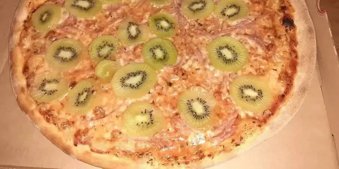a pizza topped with kiwi slices
