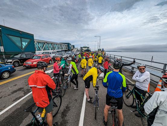 Bicycle riders in colorful cycling garb wait on the Edmonds ferry dock.