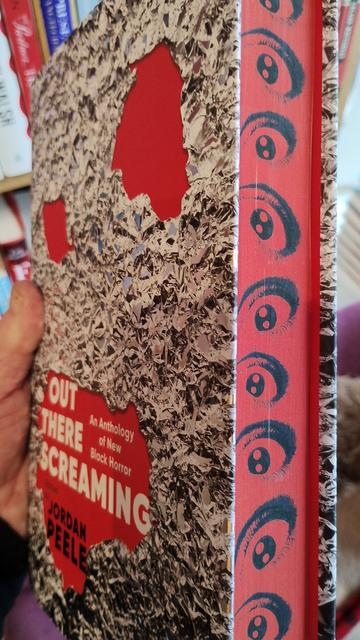 Side view of the book showing the spredges (sprayed page edges), in red with eyeballs printed on them running down the length of the book