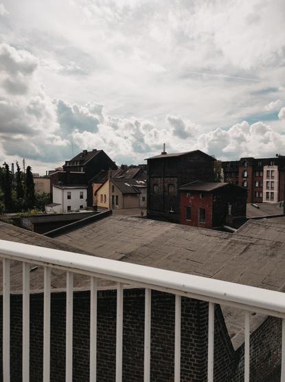 Blick auf Himmel und Hausdächer von einer Brücke aus.