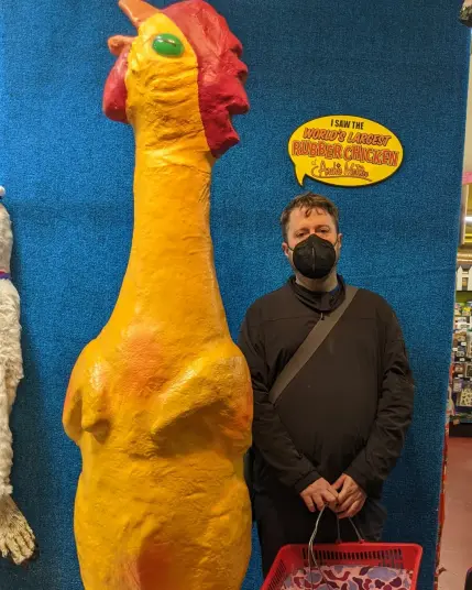 Photo of a guy posing beside a giant 2 metre rubber chicken