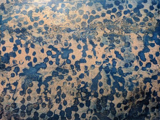 Abstract print of textured blue dots on a gold background.