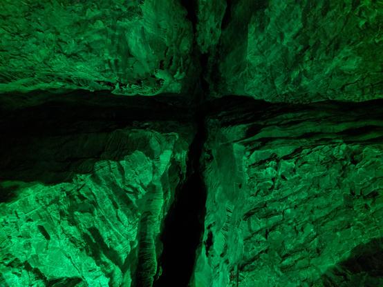 looking up at cross-jointing in limestone (calcite) in Grotte de Baume les Messieurs. Green light from cave show.
