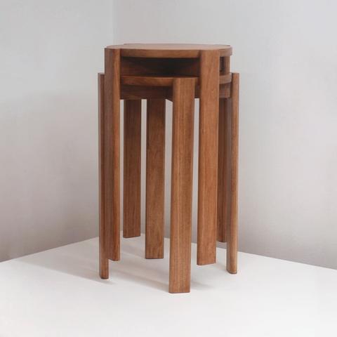 Two poplar stools stacked on top of each other. The legs allow the stools to nest together taking up less space.
