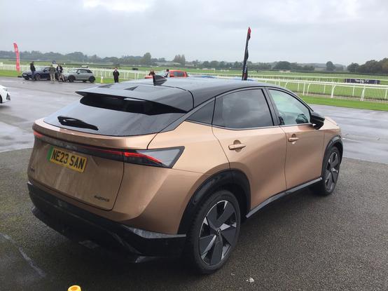 Copper metallic Nissan Ariya with black roof, rear quarter view