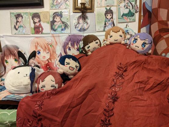 The named characters, a mix of nesoberi, plushies, and standee are arranged on a red "mountain." In the back ground is Chiya plaques on a wall.
