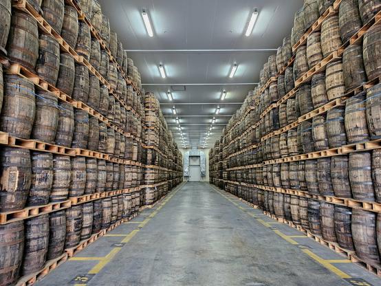 Hundreds and hundreds of wooden casks stretching into the distance inside a whisky maturation cellar