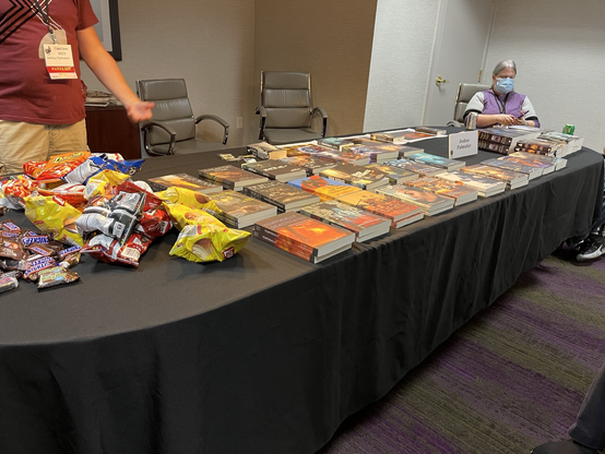 Table full of Zombies Need Brains books, plus snacks.