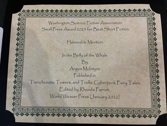 Certificate with flowery border: Washington Science Fiction Association Small Press Award 2023 for Best Short Fiction, Honorable Mention, In the Belly of the Whale by Angus McIntyre published in Trenchcoats, Towers, and Trolls:Cyberpunk Fairy Tales, Edited by Rhonda Parrish, World Weaver Press (January 2022)