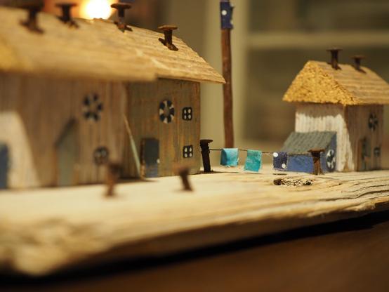 Kleine Skulptur aus Treibholz, bestehend aus 3 kleinen Häusern und einer Wäscheleine.