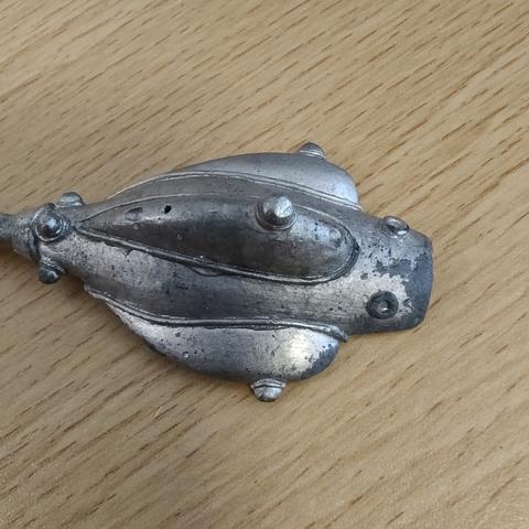 A piece of a lead spaceship miniature, with visible corrosion on the edges.