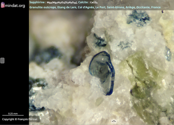A translucent blue sapphirine crystal embedded in calcite; from Occitanie, France. Photo by François Périnet, hosted by MinDat.org