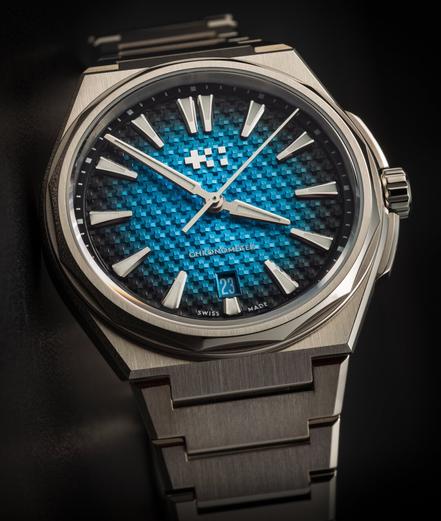 A watch with a greenish-blue textured face on an integrated bracelet
