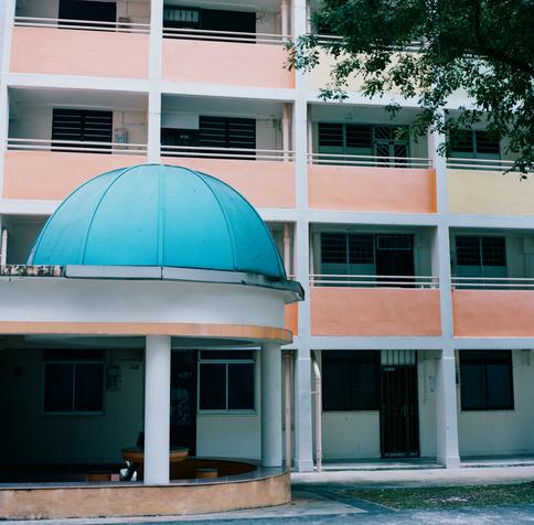 a scan of a medium format photo of some pastel orange and pink and blue old buildings in singapore