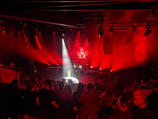 Red lit stage with an image of an rabbit. One white lamp is lightning some clothing.