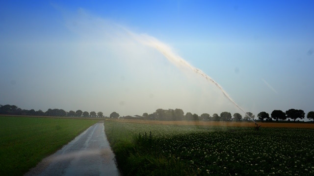 Wassersprenger über Acker und Wirtschaftsweg