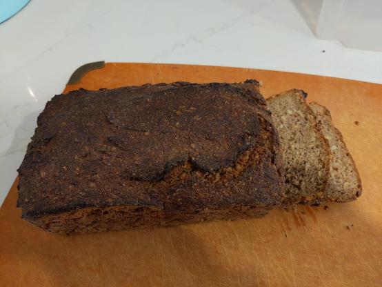 A loaf of a dark rye bread with two slices cut.
