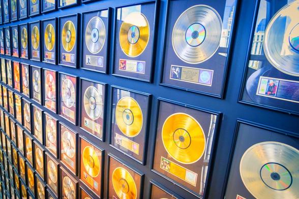 Goldene Schallplatten hängen als Preissammlung an einer Wand.