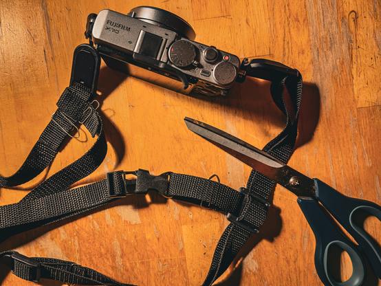 X70 with strap on a wooden table again, the 2 point strap is not connected by a diagonal one that can be loosened by a buckle. The diagonal is on one side connected via a loop on the other via a 3D printed part.