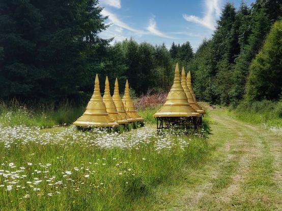 Gold pagodas sitting in a green field under a blue sky.
