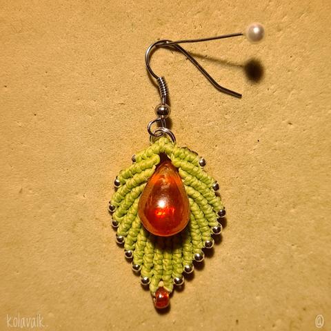 Détail de la première boucle d'oreille terminée, à l'endroit, épinglée sur le fond de mousse