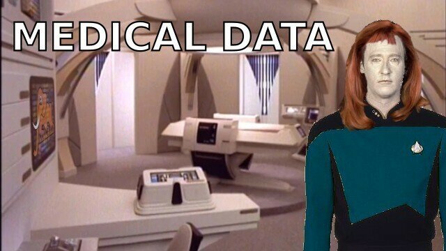 startrek tng commander data wearing a red hair wigg and a medical crewmember uniform stands in the medical bay and he is totally ....crushin it!