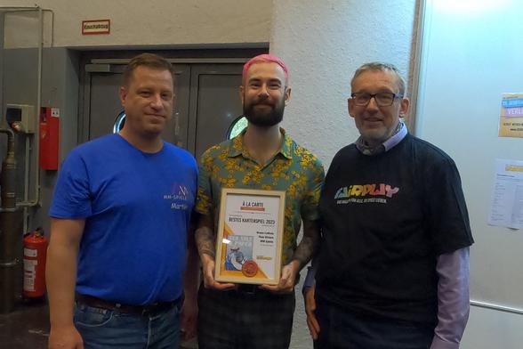 Award ceremony of the À la carte Card Game Prize 2023 to Sea Salt & Paper. Present are Martin Mader from MM-Spiele, the author Théo Rivière and Wolfgang Friebe from Fairplay Verlag.