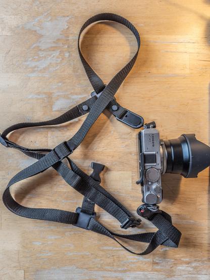 Top view of the camera strap with camera attached on a wooden table.