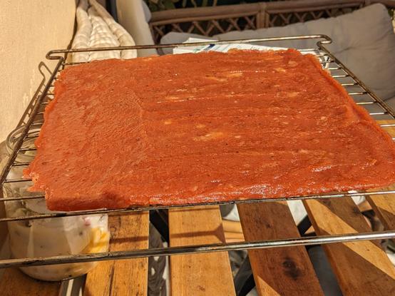Die noch nicht ganz getrocknete, braun orange schimmernde Quittenmasse auf einem Rost in der Sonne.