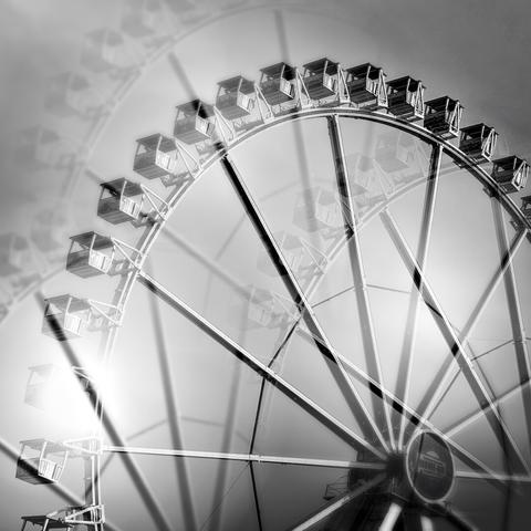 A black-and-white photo of a large ferris wheel with multiple exposure effects.