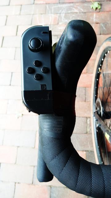 Ein schwarzer Dropbarlenker mit einem Nintendo Switch Joy-Con. Der Joy-Con ist mit schwarzem Tape am Lenker befestigt.