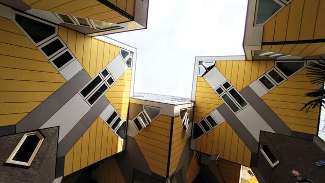 A view up into the sky from a yard between the cubehouses.

They are yellow cubes sat on a corner onto a brick tower. Along the center diagonals of the sides are the windows. A very futuristic ensemble of buildings.